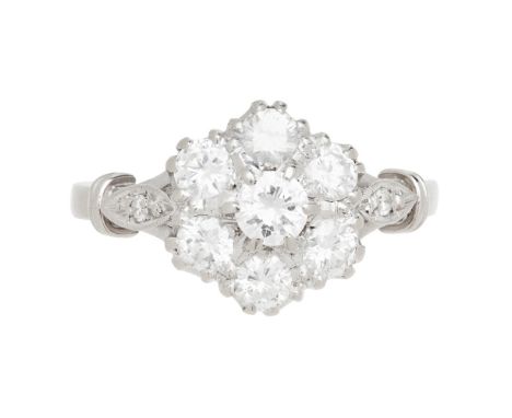 AMENDMEND TO CATALOGUE A diamond cluster ring  claw set with seven round brilliant cut diamonds, each shoulder set with a sma