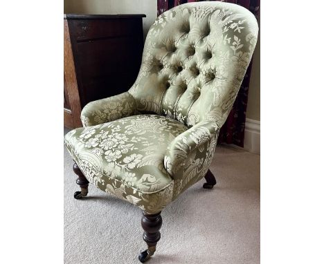 Victorian Nursing chair, buttoned back, low arms and serpentine seat on turned supports with brass sockets and ceramic caster