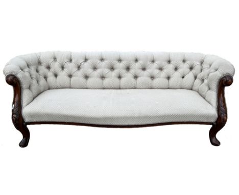 Victorian mahogany framed serpentine front sofa, deep buttoned back and outscrolled arms on cabochon carved cabriole legs wit