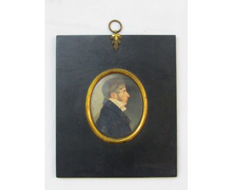 An early 19th century miniature portrait of oval form showing a bust length profile study of a gentleman in blue coat and whi