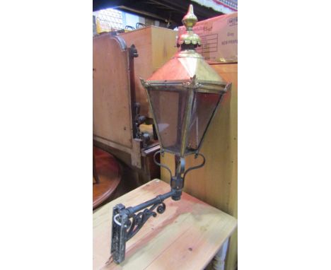 A Victorian style exterior street type lantern hood in brass of tapered form mounted on a cast alloy wall bracket 
