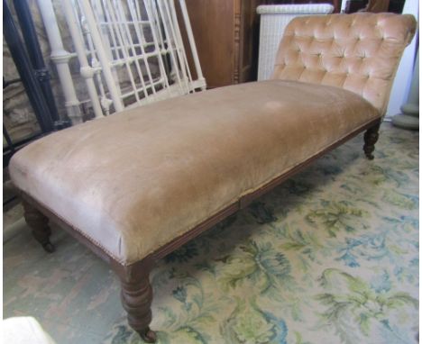 An late Victorian oak chaise lounge/day bed with upholstered seat and scrolled button back raised on oak turned tapered legs 