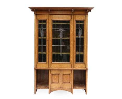 An Arts &amp; Crafts Scottish School Oak Bookcase, the overhanging top above three coloured and leaded glazed doors, above a 