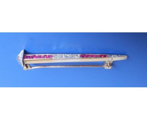 A Victorian ruby & diamond set tie pin brooch in the form of a tapering horseshoe nail, having square cut rubies and rose cut