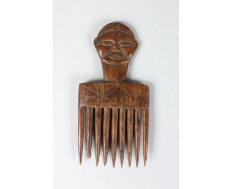 A WEST AFRICAN CARVED WOOD COMB, the handle as a head. 8ins long.