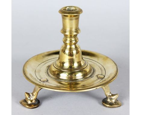 AN EARLY 18TH CENTURY DUTCH CIRCULAR BRASS CANDLESTICK on three feet. 5.5ins high.