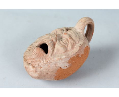 A ROMAN TERRACOTTA LAMP with a face and handle. 6ins long.