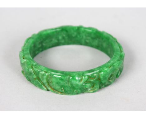 A CHINESE CARVED APPLE GREEN JADE BANGLE.