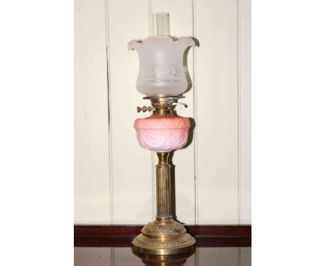 Brass column oil lamp with pink moulded reservoir and frosted and etched glass shade.