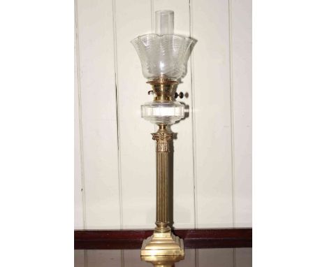 Brass corinthian column oil lamp with clear glass reservoir and shade.