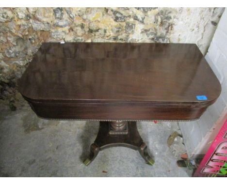 A William IV mahogany fold over card table supported on ring turned column of vase shaped form, on quadrofoil base and brass 