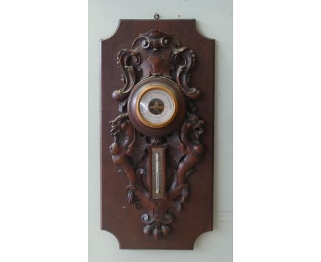 Wall barometer and thermometer in carved oak frame standing on a plaque style background