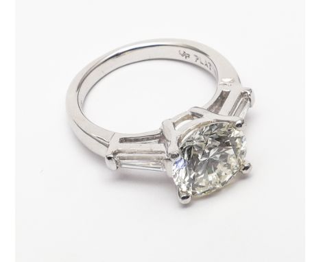 Diamond solitaire ring set with a circular brilliant cut diamond weighing 3.39 carats in platinum claw setting with baton dia