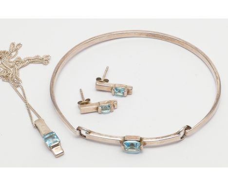 Modern silver and blue topaz set suite of jewellery comprising bangle, ear studs and pendant necklace on fine chain.