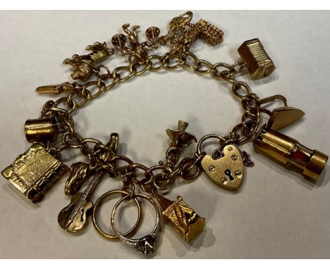 A 9ct gold curb link charm bracelet, love heart clasp, assorted charms including miner's lamp, church, Big Ben, iron, lion, i