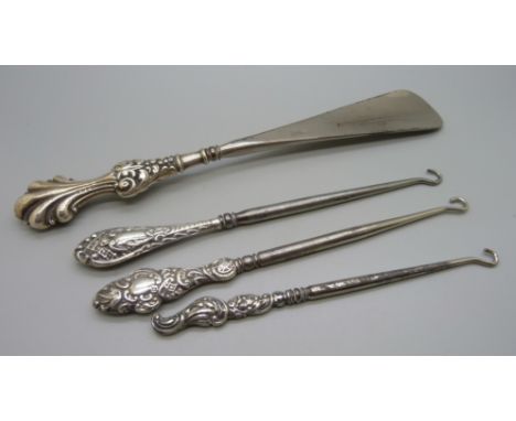 Three silver mounted button hooks and a shoe horn 
