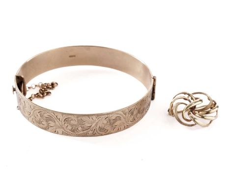 A 9ct yellow gold bangle, engraved scrolling foliate decoration, with safety chain, 65mm wide; and a yellow gold brooch, stam