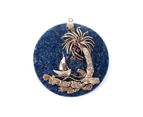 A lapis lazuli pendant, of disc form, overlaid with a rose gold tropical sailing scene, depicting a ruby set palm tree and a 