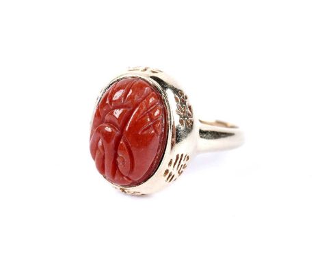 A carved sardonyx cabochon dress ring, the pierced setting of Chinese design, in 14ct yellow gold, size R, 4.8g gross.