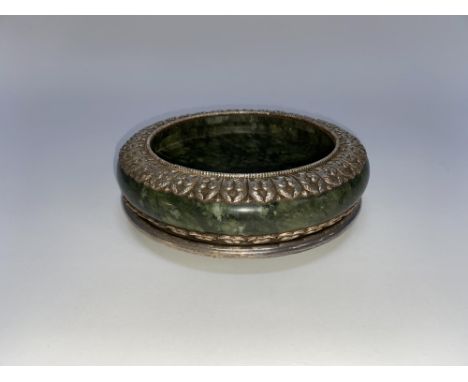 A Chinese spinach jade circular bowl and stand, with decorative silver coloured mounts, diameter 18cm