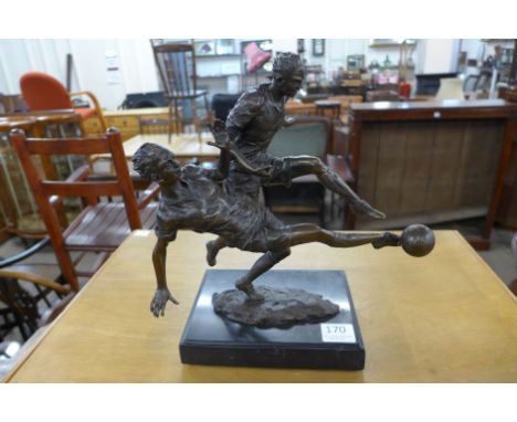 A bronze figure of two footballers, on black marble base
