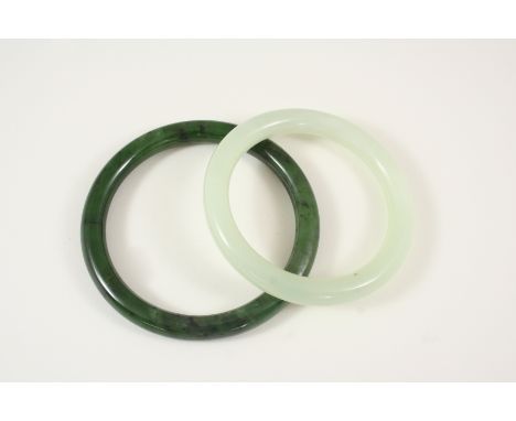A MOTTLED GREEN JADE BANGLE together with another jade bangle.