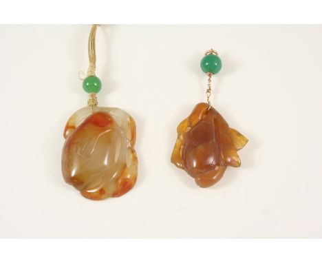 A CARVED JADE PENDANT depicting fruit hanging from a branch, 4.5cm. long, together with another similar carved jade pendant, 