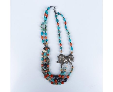 This vintage multi strand necklace with a hook clasp features beaded coral, turquoise, and jasper, textured silver toned prol