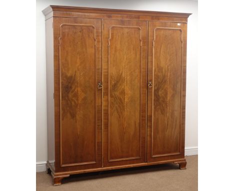 Early 20th century walnut triple wardrobe, projecting cornice, fitted with hanging rail and three linen slides, shaped bracke