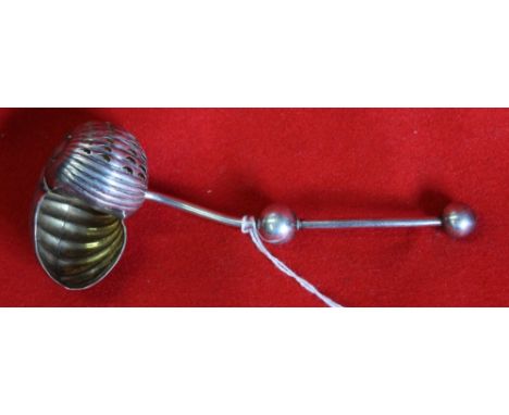 A white metal sifting ladle, the bowl in the form of a shell with gilded interior