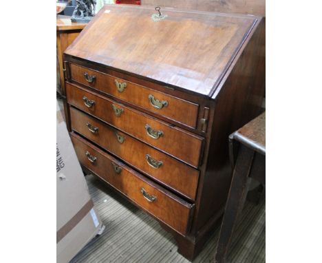 A George III part walnut veneer writing bureau, the fall reveals fitted interior, over four drawers with brass handles on bra
