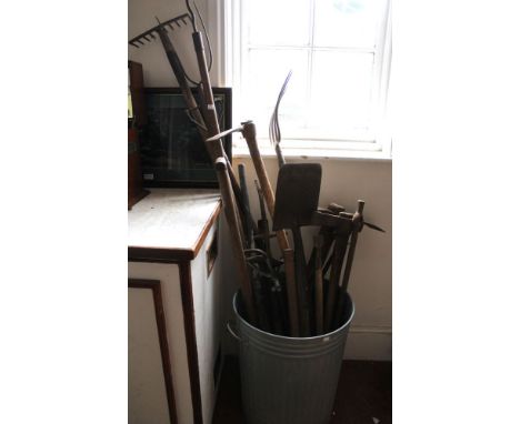 A metal bin containing a wide selection of groundwork/farm tools