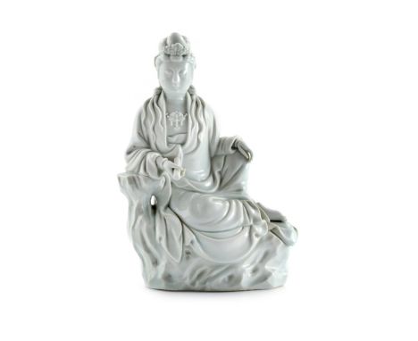 A CHINESE BLANC DE CHINE FIGURE OF GUANYIN LATE QING DYNASTY Sitting on rockwork holding a scroll, 24.8cm. 