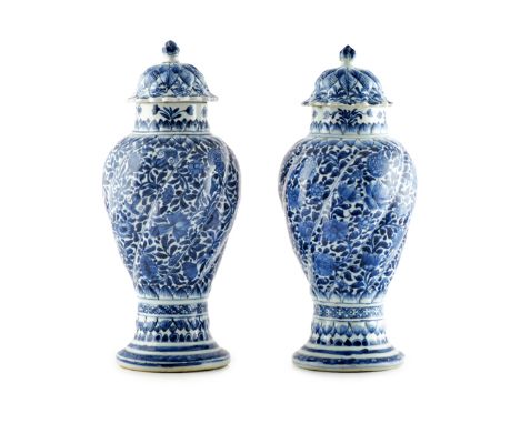 A PAIR OF CHINESE BLUE AND WHITE MOULDED VASES AND COVERS KANGXI 1662-1722 Each with twisted panels of dense foliate designs 