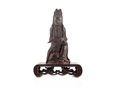 A CHINESE CARVED BUFFALO HORN MODEL OF GUANYIN 19TH CENTURY Seated, wearing flowing robes and holding a ruyi sceptre in her f