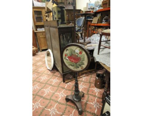 A mid 19th century mahogany pole screen with floral woolwork tapestry raised on bun feet.