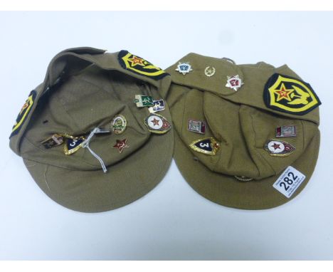 Two Russian Army Caps with Various Enamel Russian Style Badges