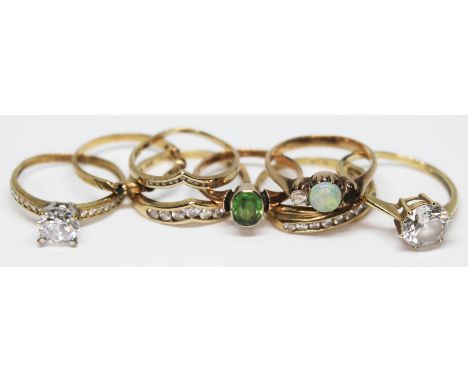 A group of eight 9ct gold rings including one set with a peridot and one set with an opal, various other settings and marks, 