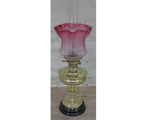 A brass oil lamp with etched cranberry glass shade, height 67cm.Condition: a few minor dents to the brass as pictured, glass 