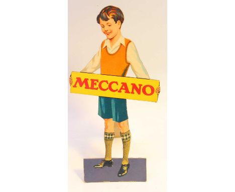 An original Meccano shop display card comprising a boy wearing a red Jumper and holding a rectangular Meccano sign, complete 
