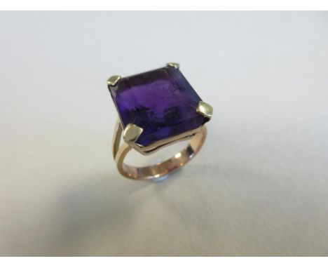 A large single stone amethyst ring, the rectangular step cut amethyst of rich purple hue, four claw set to bifurcated shoulde