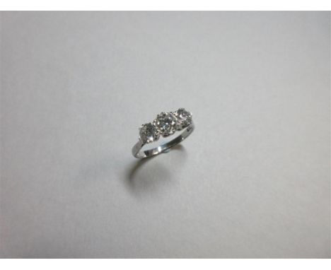 A three stone diamond and platinum ring, the graduated old round brilliant cut diamonds claw set to a coronet gallery and pla