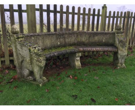 A composite stone curved bench, with raised panel back and on seated lion end supports 91 x 233 x 53cm (35 x 91 x 21in)  