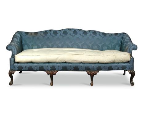 A George III style sofa, with a shaped back and outscrolling arms, upholstered in a woven blue fabric, on leaf and scroll car