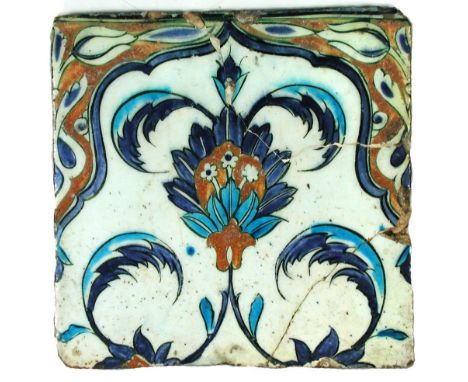A 16th century Islamic Turkish Iznik square tile, decorated in blue and iron red with flowers and scrolling foliage, within a