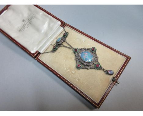 An Arts & Crafts opal, ruby and enamel pendant necklace, designed as a pierced filigree work diaper with a central oval black