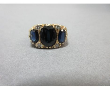 An Edwardian style 18ct gold sapphire and diamond ring, set with three graduated oval cut midnight blue sapphires with four r