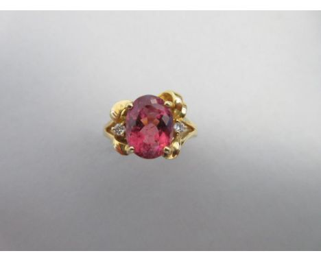 A pink tourmaline and diamond ring set in 18ct gold, the large oval cut pink tourmaline between two small round brilliant cut