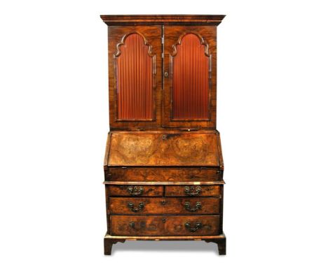 A Queen Anne walnut bureau bookcase, with arched glazed doors enclosing a fitted interior of small drawers and a central cupb