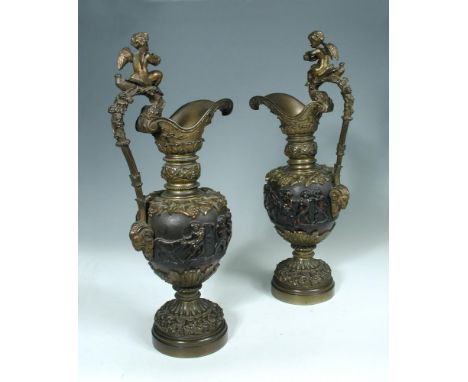A large pair of Renaissance revival patinated bronze ewers, each cast with a frieze of Bacchic putti and mounted with a scrol